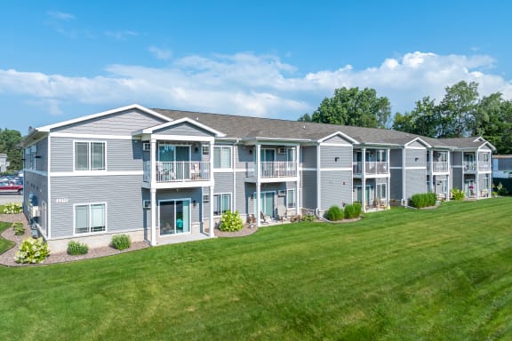 the view of an apartment building with a green lawn