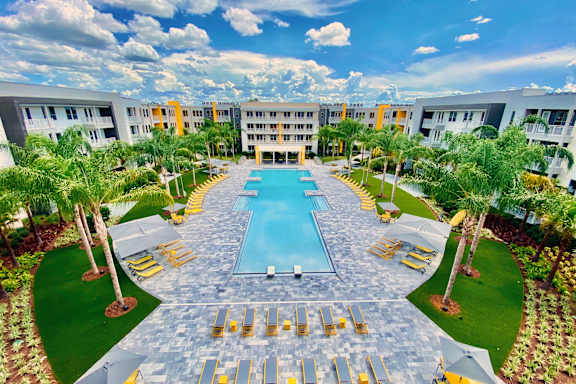 A large swimming pool surrounded by palm trees and lounge chairs.