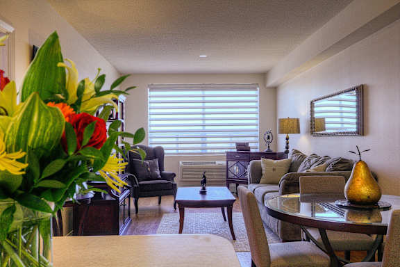 A living room with a couch, chairs, and a table with a pear on it.