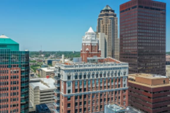 A cityscape with a variety of buildings including a tall red brick building with a pointed roof.