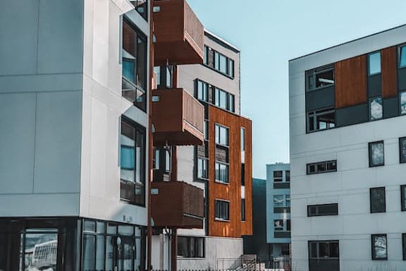 A modern building with a white facade and a brown balcony.