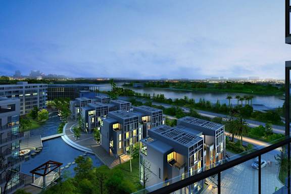 A modern residential complex with a river view at dusk.