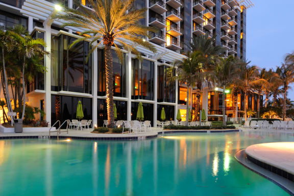 a large swimming pool with palm trees in front of a building