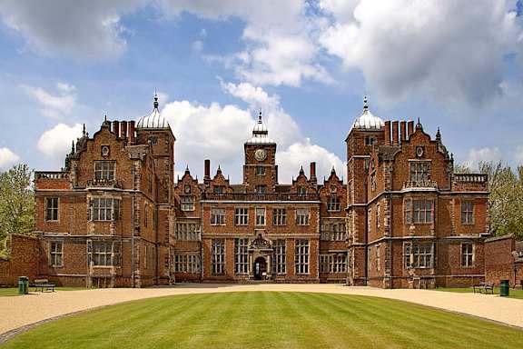 A large, historic red brick building with a green lawn in front.