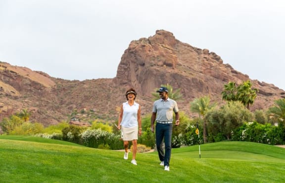 a man and a woman walking on a golf course