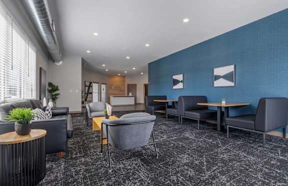 A modern waiting room with grey and blue walls and a variety of seating options.