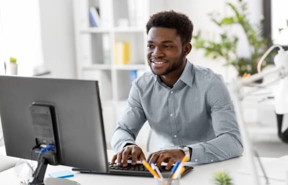 a man sitting at a desk using a laptop computer