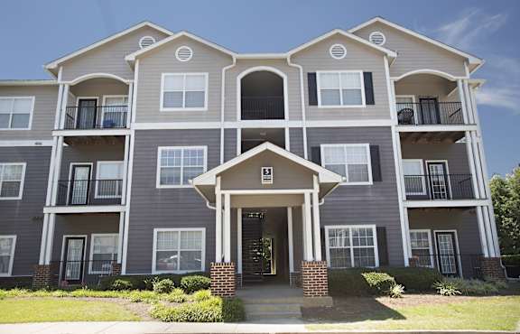 A large apartment building with a front entrance and multiple balconies.