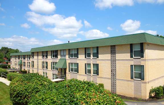 A building with a green roof and a brick facade with a green awning.