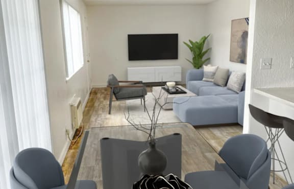 A living room with a grey sofa, grey armchairs, a grey coffee table, a flat screen TV, and a plant.
