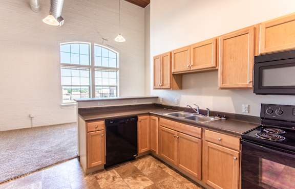A kitchen with wooden cabinets and black appliances.