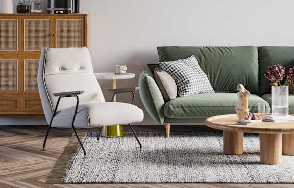 A living room with a green couch, a white chair, and a wooden cabinet.