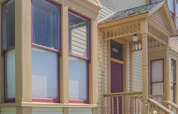 A yellow house with a balcony and a window.