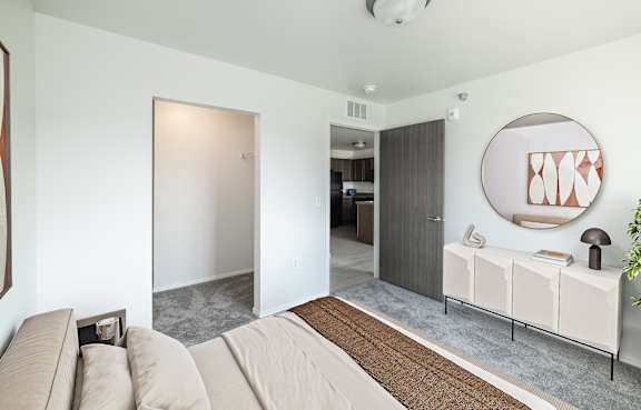 A modern living room with a grey carpet and a wooden dining table.