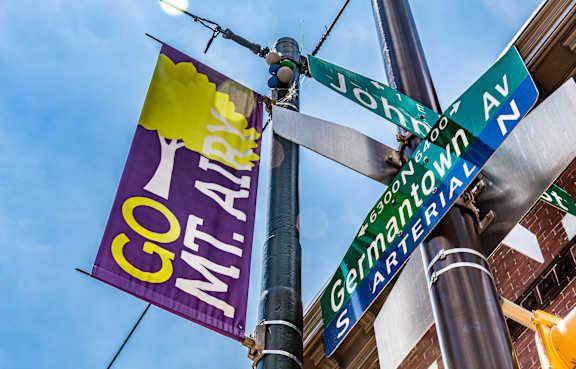 A street sign pole with a sign for Germantown and a banner that says Go Mt. Airy.