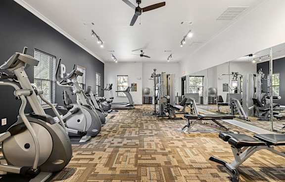 A gym with a variety of equipment including treadmills, stationary bikes, and weight machines.