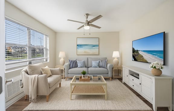 A living room with a grey couch, a coffee table, and a painting of a beach scene on the wall.
