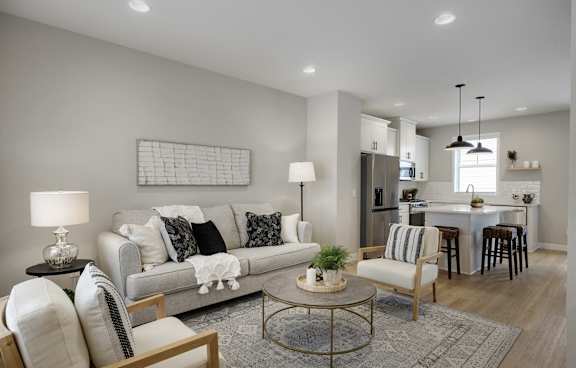A modern living room with a grey sofa, a coffee table, and a kitchen in the background.
