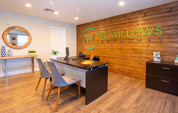 a room with a desk and chairs and a mirror on the wall