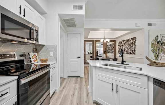 A kitchen with white cabinets and a black stove top oven.