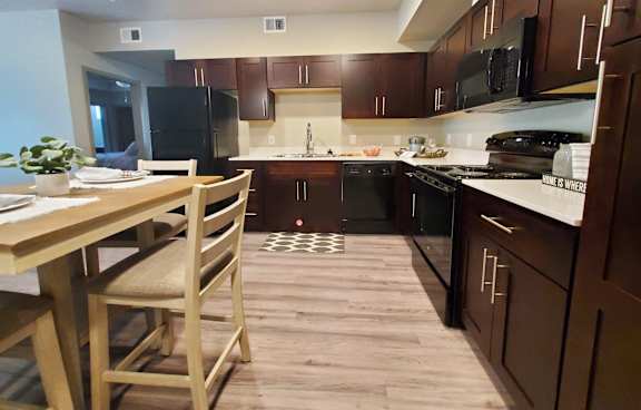 A kitchen with wooden floors and brown cabinets.