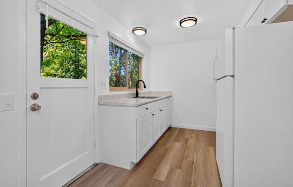 A white kitchen with wood floors and a window.