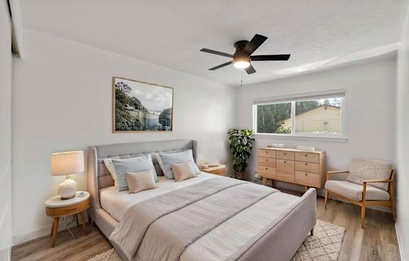 A bedroom with a large bed, a chair, and a ceiling fan.