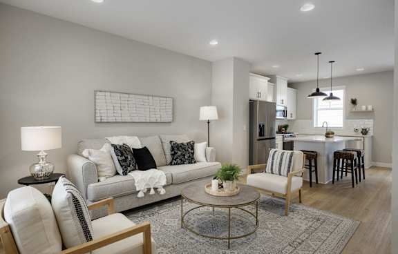 A modern living room with a grey sofa, a coffee table, and a kitchen in the background.