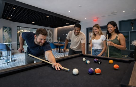 A group of people playing pool in a room.