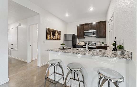 a kitchen with a bar and stools in front of a counter top with bar