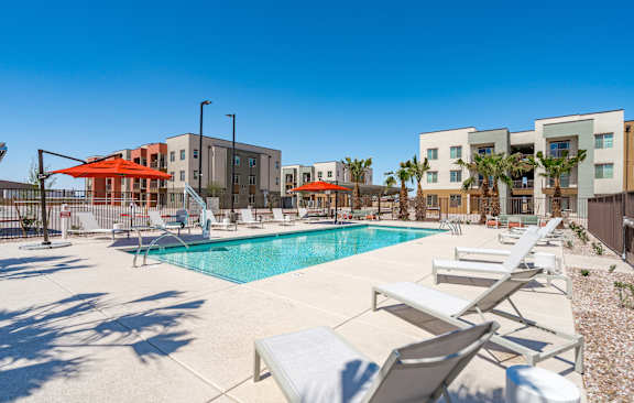 A pool surrounded by sun loungers and umbrellas.