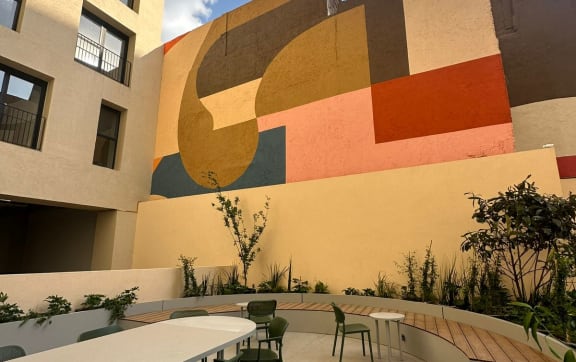 a patio with tables and chairs in front of a wall with a mural
