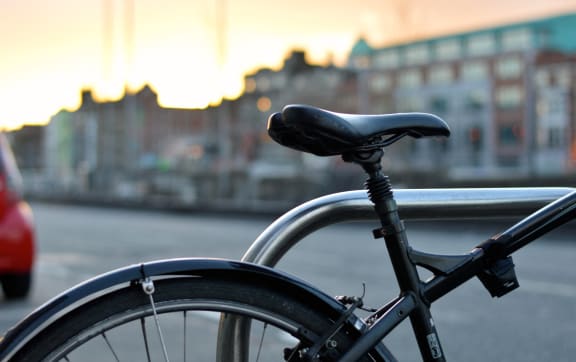 a bike parked next to a railing on a city street