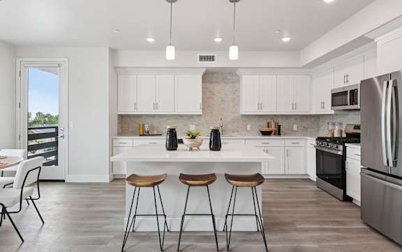 A kitchen with white cabinets and a black refrigerator.