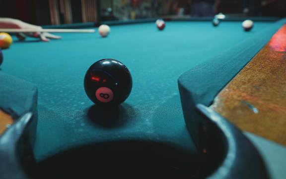 A pool table with a black ball in the foreground and several other balls scattered around.