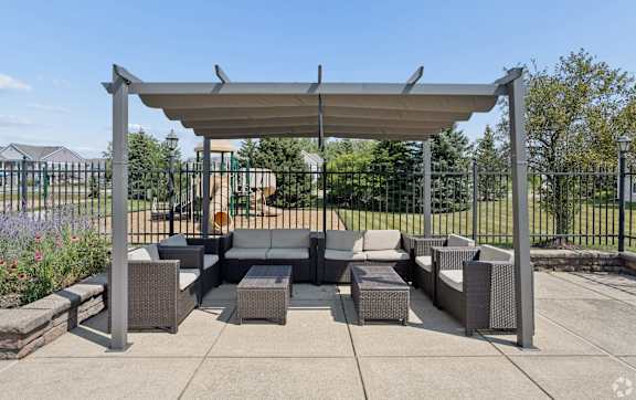 A patio with a grey sofa and a grey table under a grey canopy.
