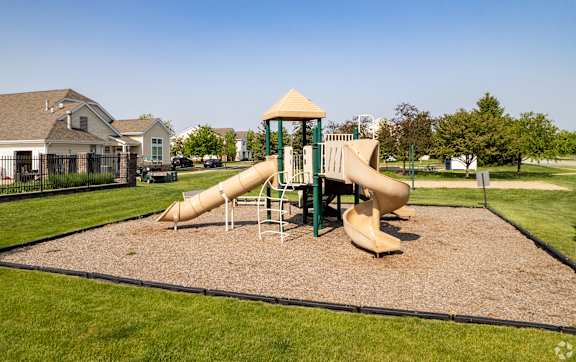 A playground with a yellow and green slide.