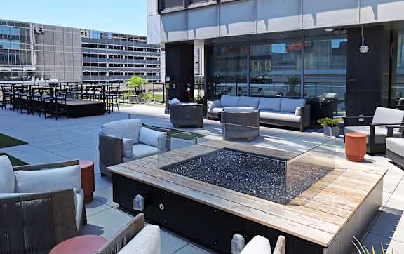 A modern outdoor seating area with a fire pit and comfortable seating.