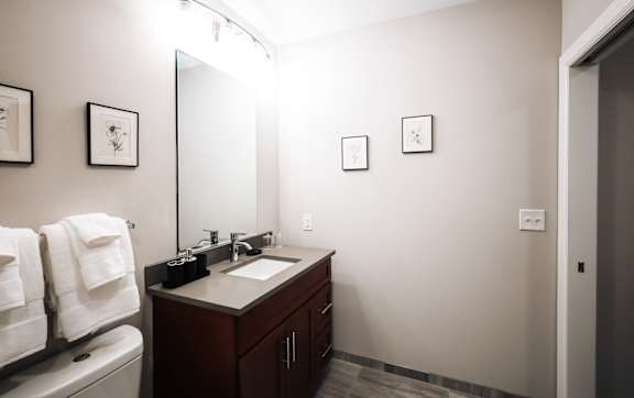 A bathroom with a toilet, sink, and mirror.