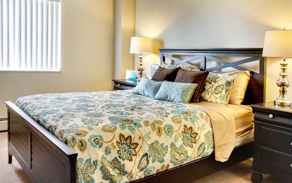 A bed with a floral patterned comforter and a wooden headboard.