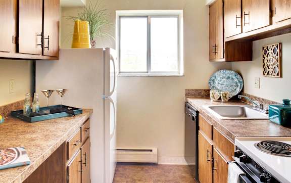 A kitchen with a white refrigerator and wooden cabinets.