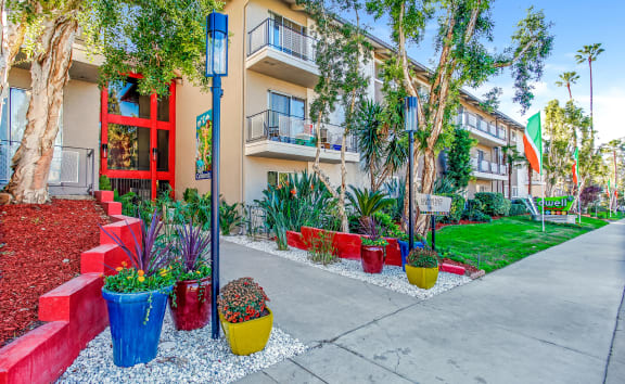 a walkway with flowers and trees in front of an apartment building at Dwell Apartment Homes, California, 92507