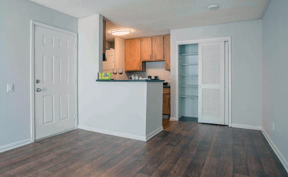 an empty living room and kitchen with a door to the closet