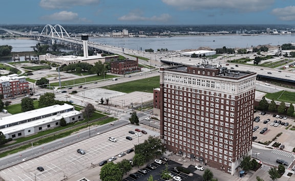 A large red brick building is in the foreground of a city scene.