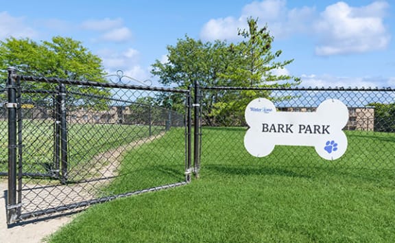 a park with a fence and a sign in the grass
