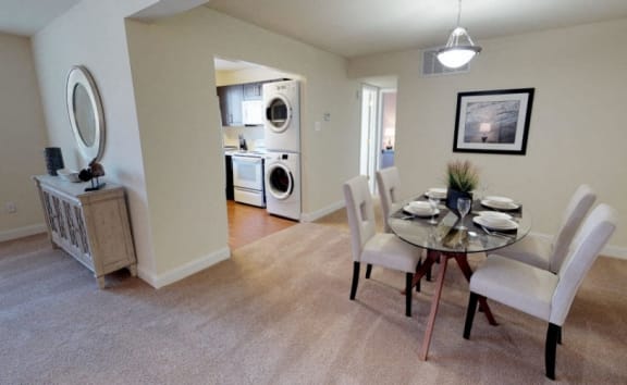 a dining room and living room with a table and chairs and a washer and at Somerset at Towson Apartments, Towson, MD, 21204