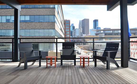 A wooden deck with chairs and a table overlooking a city skyline.