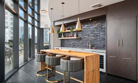 A modern kitchen with a wooden island and grey bar stools.