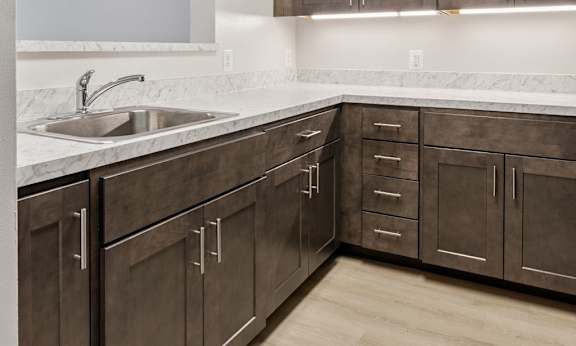 A kitchen with brown cabinets and a white sink.