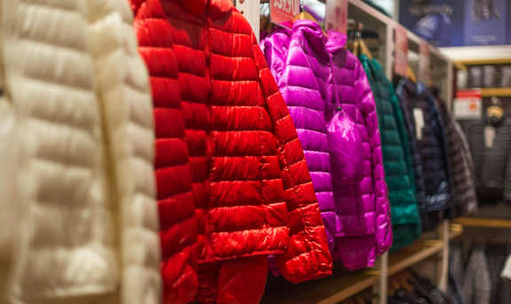 A row of puffy jackets in red, purple, and green.